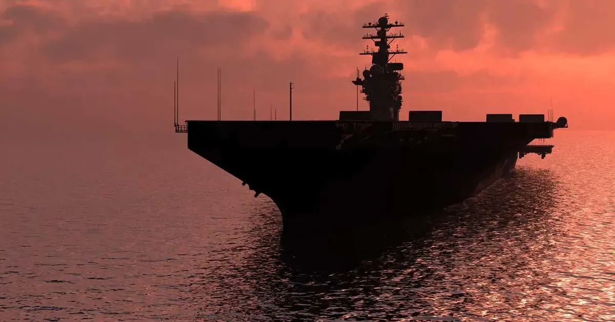 Aircraft carrier silhouetted on the ocean at sunset