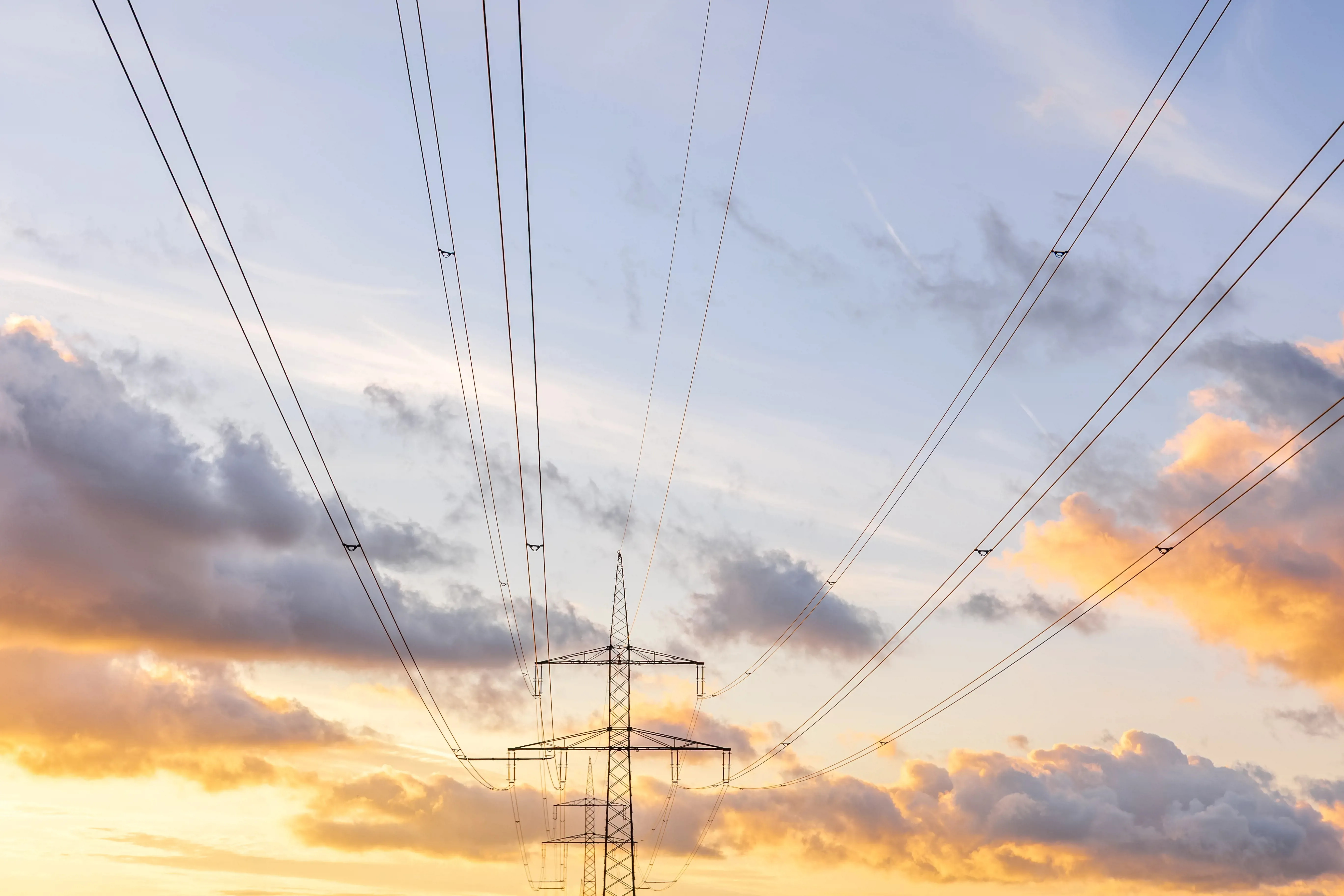 Transmission lines and pylon against a sunset sky